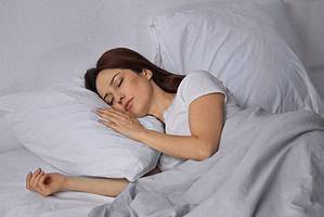 brunette woman sleeping on bed in morning