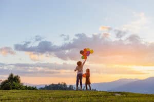 Two cute little girls playing on mountain park with air balloons at sunset. Best friends.