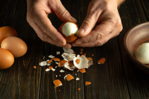 Chef hands peel boiled eggs for preparing a national dish on the kitchen table. Healthy egg diet concept